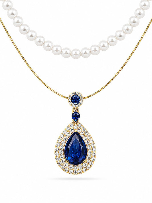 Faux pearl strand and gold-plated cable chain featuring royal blue pear-cut sapphire CZ double halo pendant with oval blue CZ bail — white background